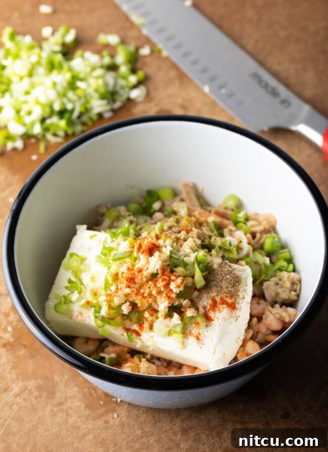 A medley of chopped seafood, herbs, and cream cheese in a white bowl.