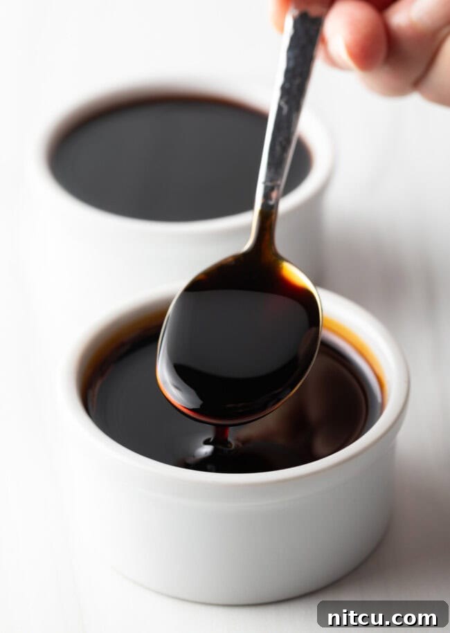 Two white ramekins of sauce. One closest to camera has a metal spoon with a spoonful showing to camera.