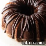 Top down view, circular chocolate sour cream bundt cake with a thick chocolate glaze drizzled on top.