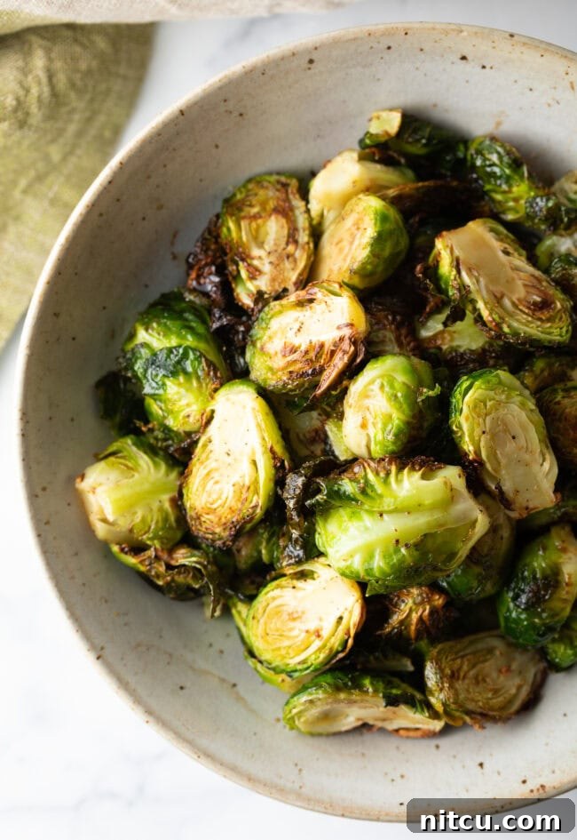 A beautifully presented white bowl of crispy air fryer Brussels sprouts, perfect for serving.