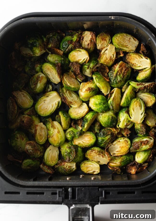 Top-down view of perfectly crispy air-fried Brussels sprouts halves in an air fryer basket, ready to be served.