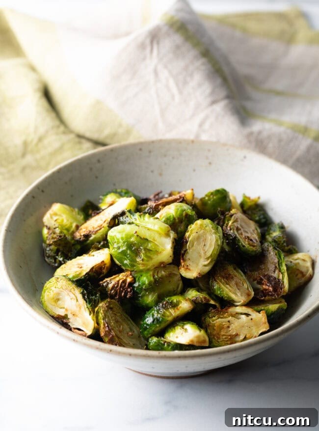 A white bowl showcasing a generous serving of perfectly crispy air fryer Brussels sprouts.
