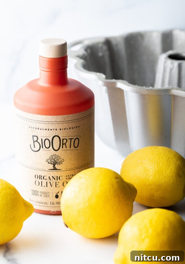 The essential ingredients laid out: a bottle of premium olive oil, representing quality, and four bright, fresh lemons, signaling the vibrant citrus heart of the recipe.