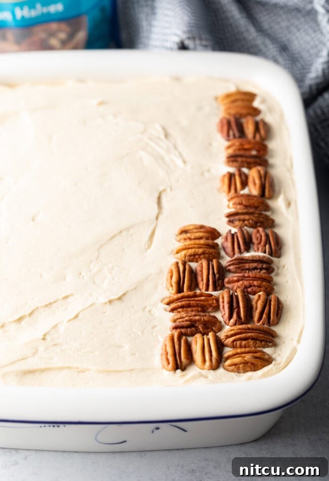 Adding nuts to the top of the frosted cake.