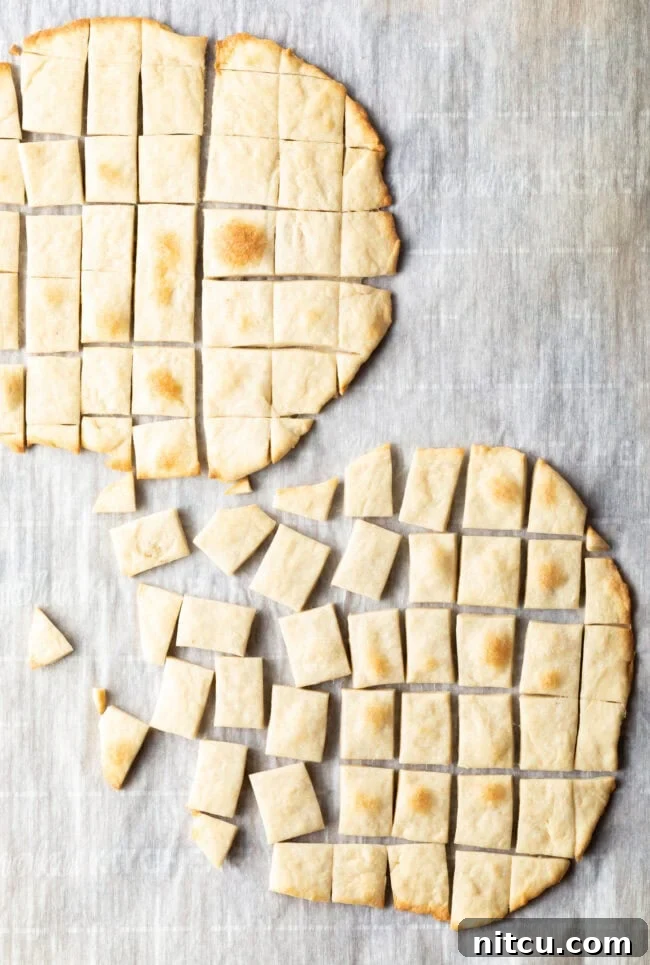 Two pieces of unleavened bread laying on a gray background, one of which has been sliced into small squares for communion.