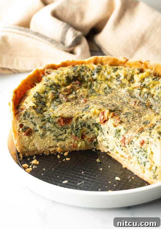 Close-up of a deep dish vegetarian quiche cooling, showing the tall, golden-brown crust and vibrant filling.
