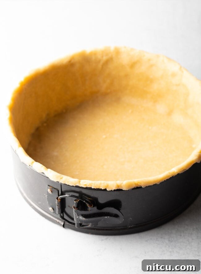 Rustic pie dough perfectly lining a deep dish springform pan, showing the tall sides and ready for blind baking.