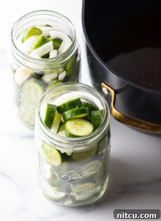 Cucumbers sliced into discs and filled into two large glass jars.