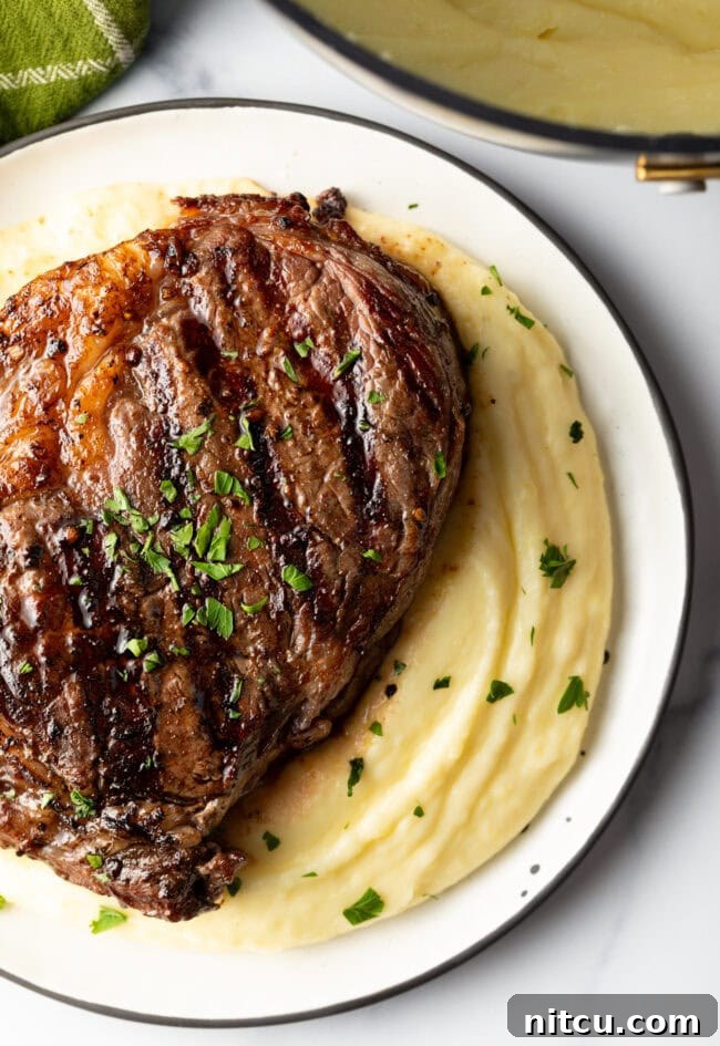 Grilled steak on top of a bed of whipped potatoes.