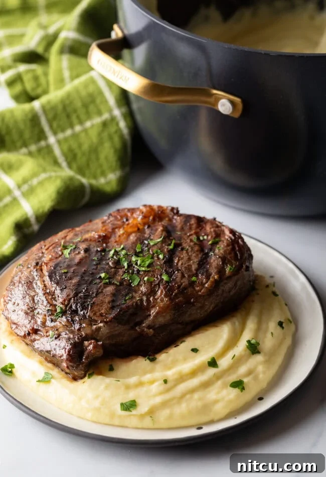 Grilled steak on top of a bed of whipped potatoes.