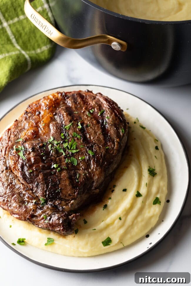 Grilled steak on top of a bed of whipped potatoes.