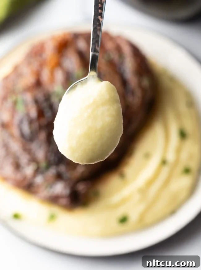 Grilled steak on top of a bed of whipped potatoes. A spoonful of potatoes is shown to camera.