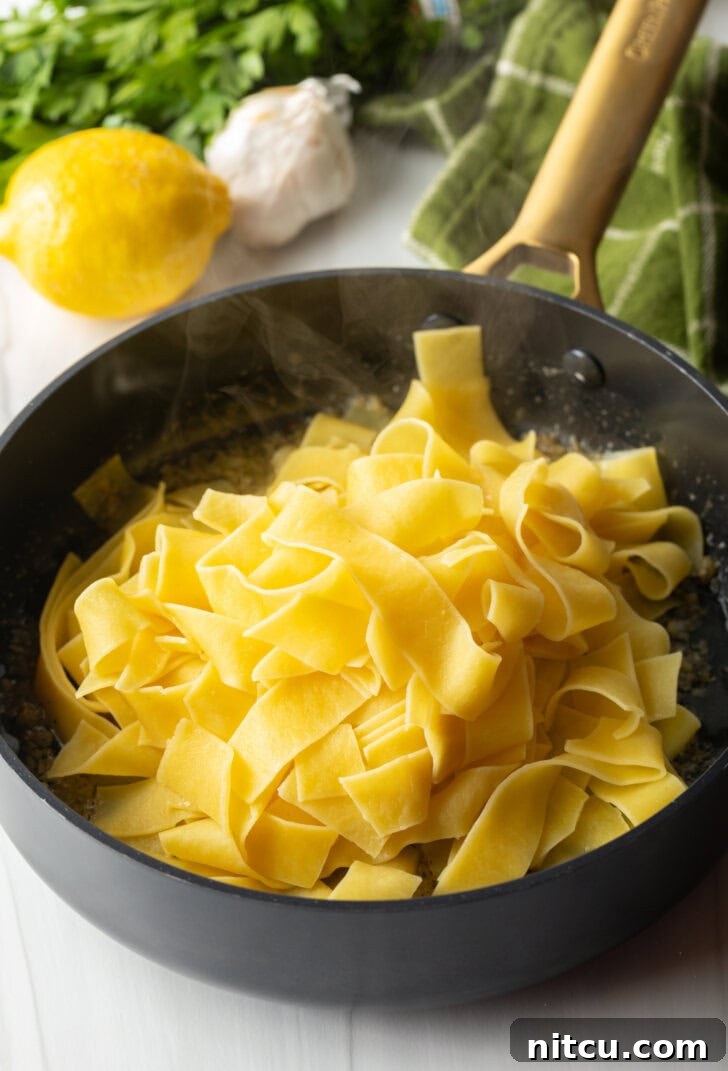 Black skillet with cooked buttery pasta.