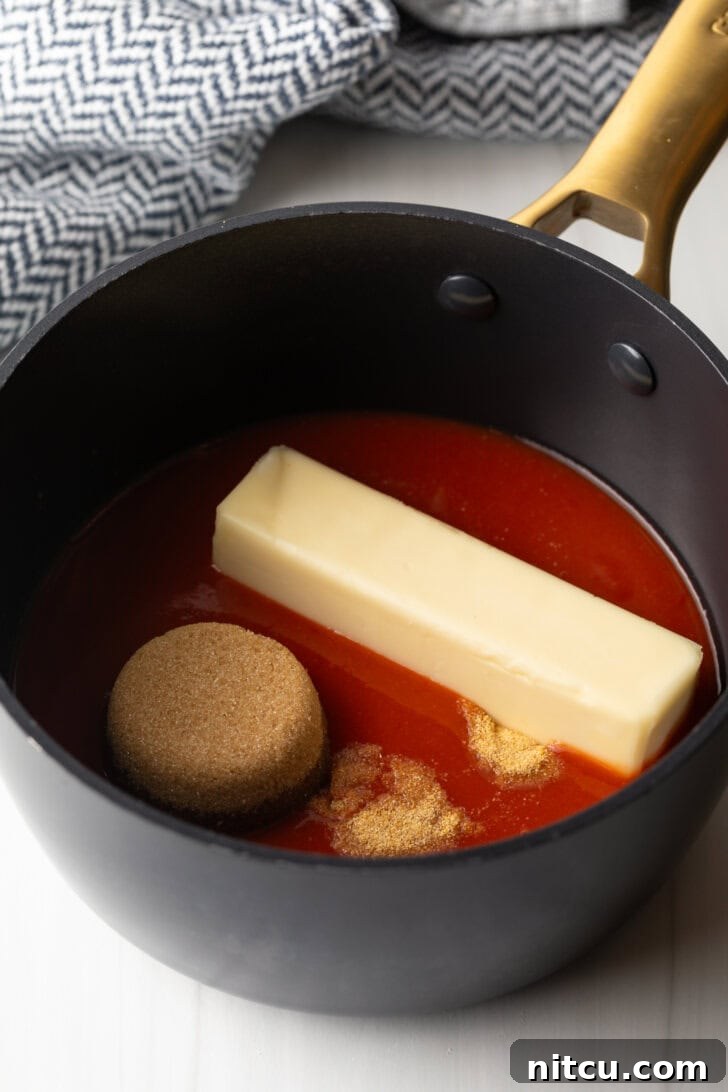 Black sauce pot with Frank's RedHot, stick of butter, and scoop of brown sugar.