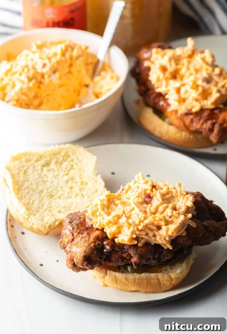 Open face fried chicken breast sandwich, with serving of pimento cheese on the chicken.