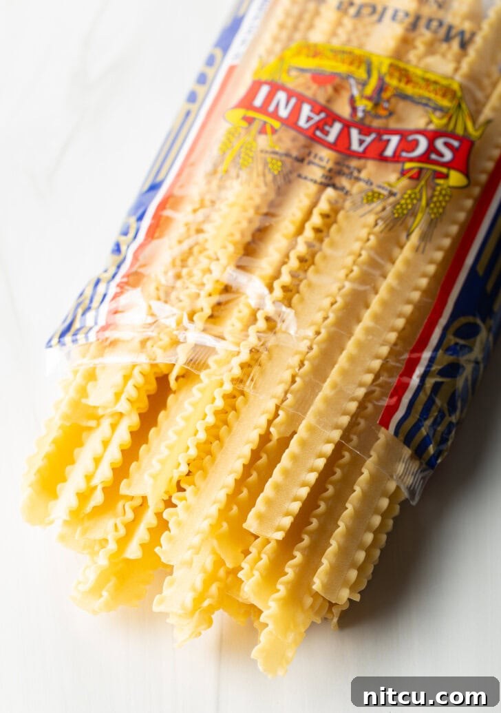 An open package of Mafalda pasta, showcasing its distinctive ruffled edges, ready to be broken into pieces for the lasagna soup.