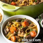 White bowl of noodle soup with meat and veggies.