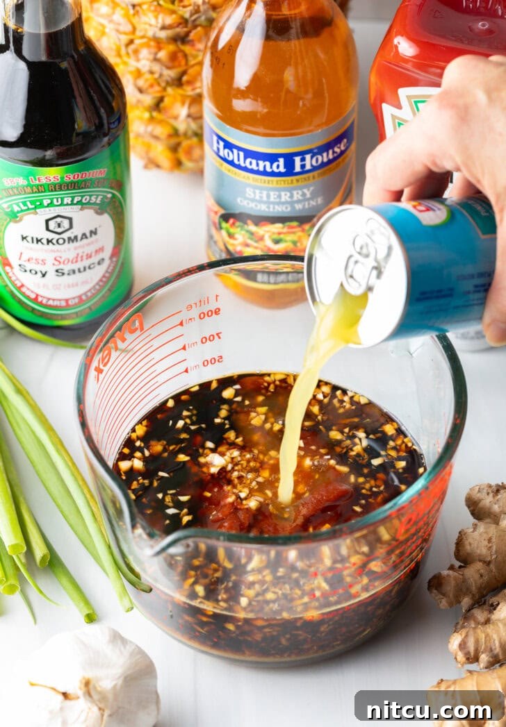 Hand adding pineapple juice from a can into a huli huli chicken marinade in a large glass measuring cup, beginning the preparation.