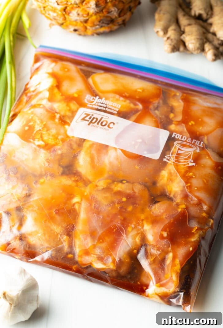 Raw chicken pieces in a plastic ziploc bag with Hawaiian chicken pineapple marinade, ready for refrigeration.