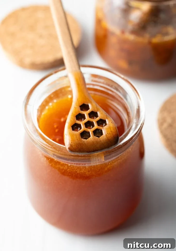 A vibrant spread of ingredients for Hot Honey Chicken, neatly arranged on a rustic wooden surface, including fresh chicken breasts, pickle juice, flour, cornstarch, various spices, milk, eggs, and a prominent jar of honey.