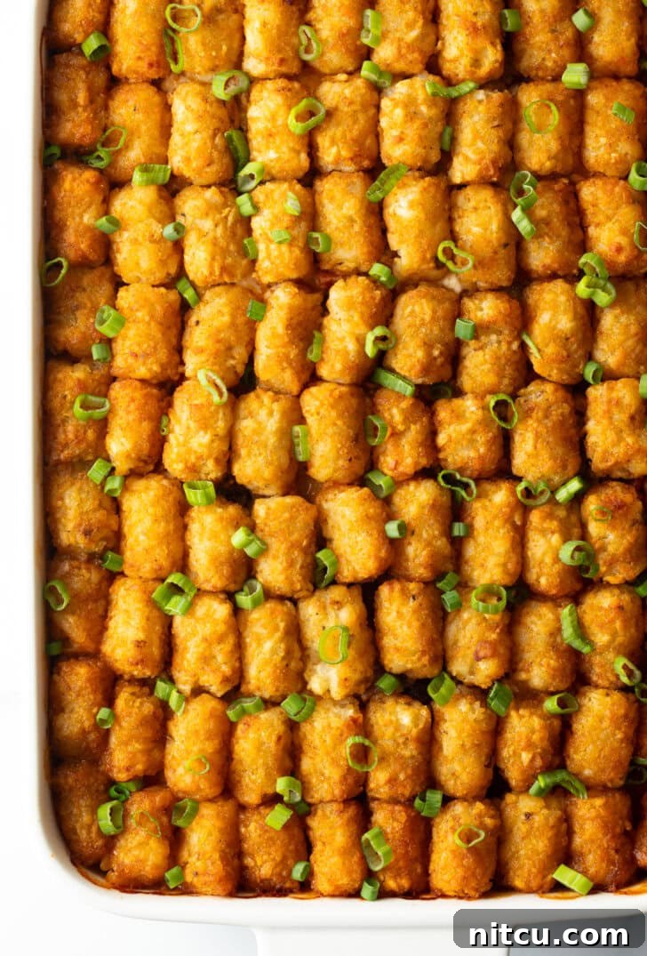 Fully baked cowboy tater tot casserole with neat rows of tater tots on top, ready to be served.