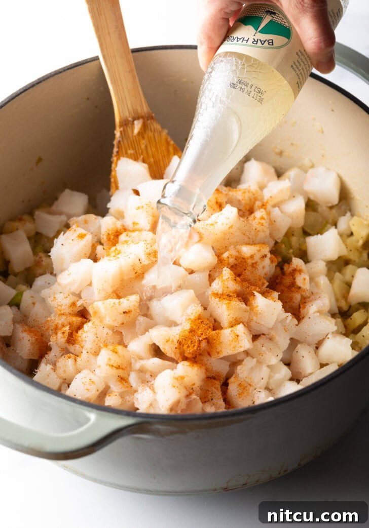 Pouring clam juice into the pot of chopped seafood.