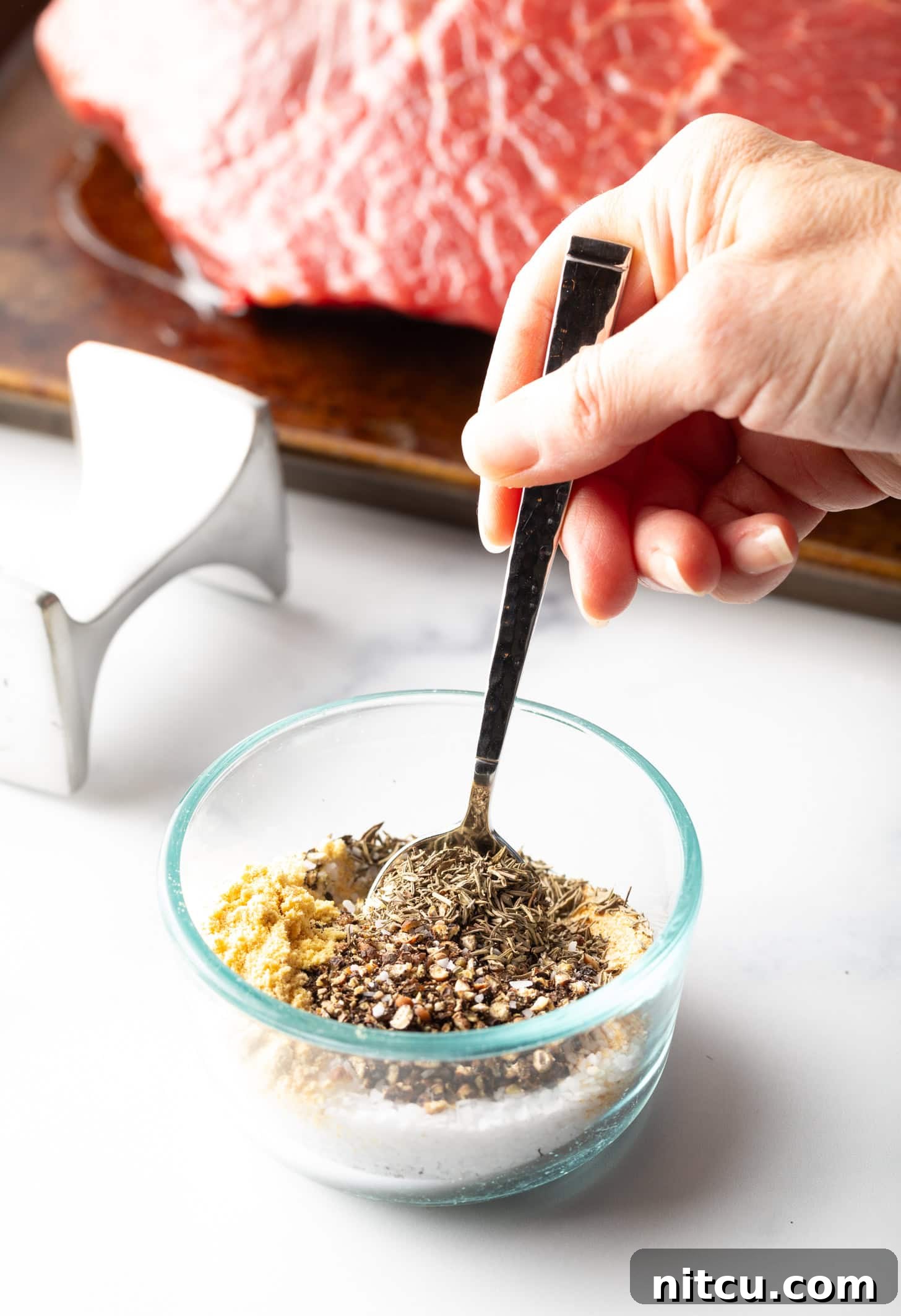 Hand stirring seasoning mix together in a small glass bowl.