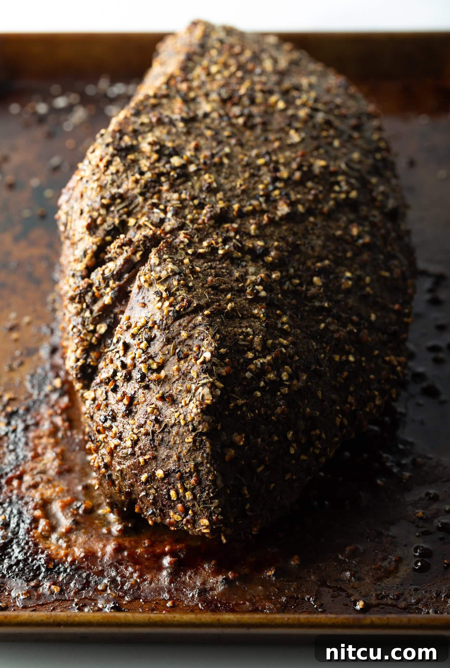 Top down view cooked beef round roast on a metal baking pan.