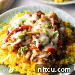 Chori pollo (chicken chorizo) covered in cheese on a bed of yellow rice.