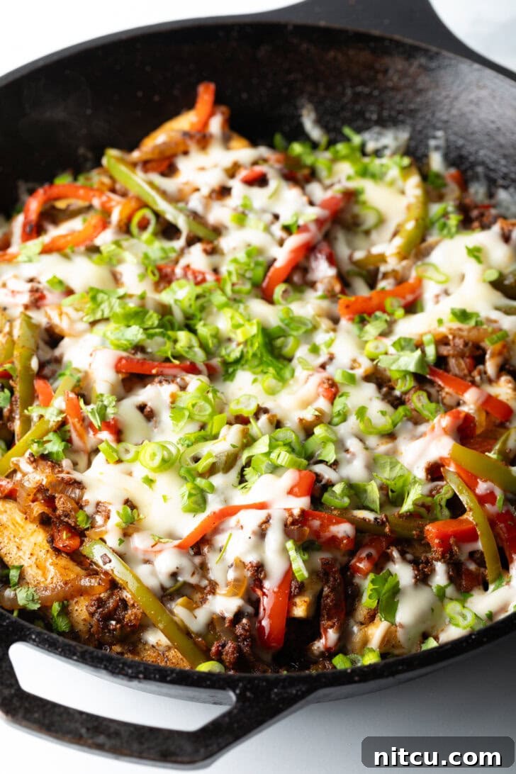 A full cast-iron skillet of Chori Pollo, adorned with melted cheese and a sprinkle of green onions, ready to be served, showcasing its vibrant appeal.