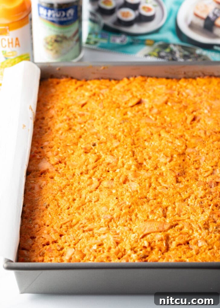 The fully assembled and cooked salmon sushi bake pressed into a rectangle baking pan, with all layers visible and ready for slicing.
