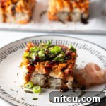Square of salmon sushi bake on a white plate with garnishes.