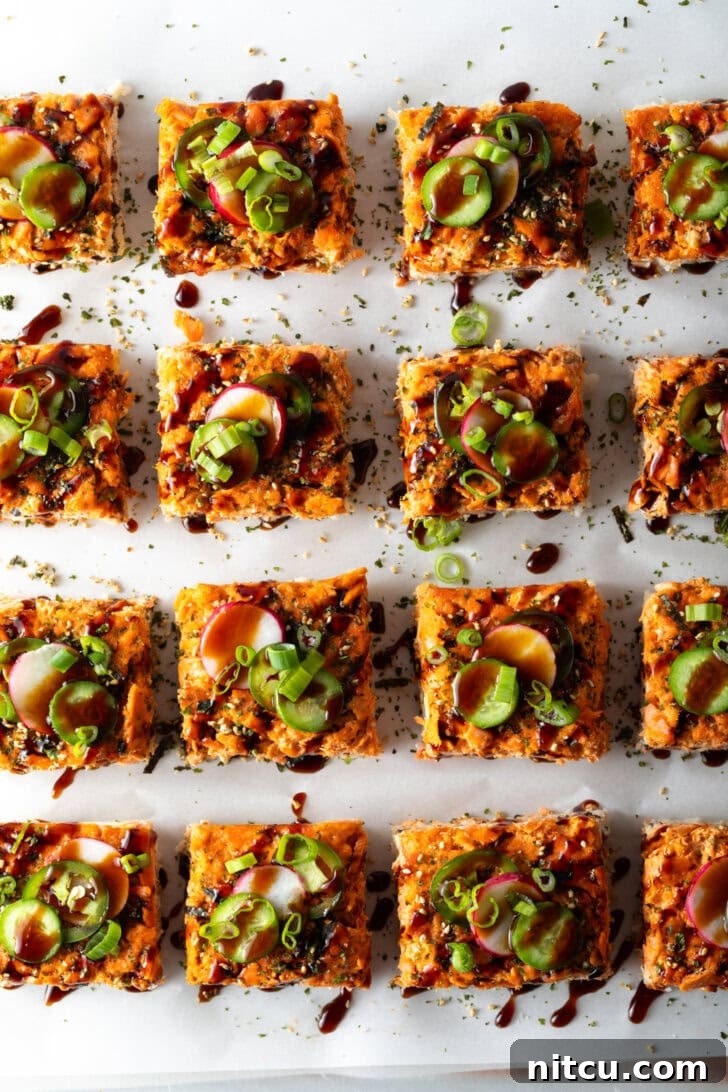 Rows of perfectly cut square slices of salmon sushi bake arranged neatly on a baking sheet, ready for serving.