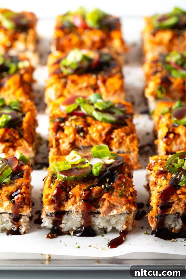 Another perspective of rows of square slices of salmon sushi bake on a baking sheet, showcasing the perfect golden-brown crust.