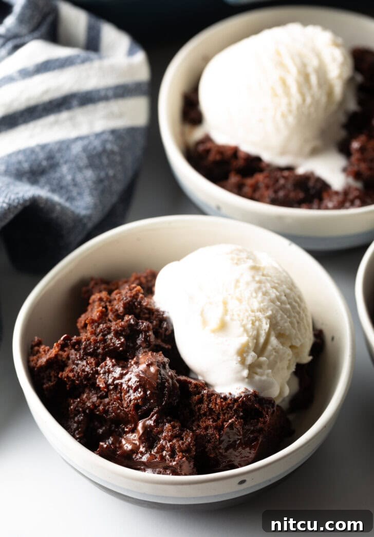 White bowl with serving of chocolate lava cake and a scoop of vanilla ice cream.