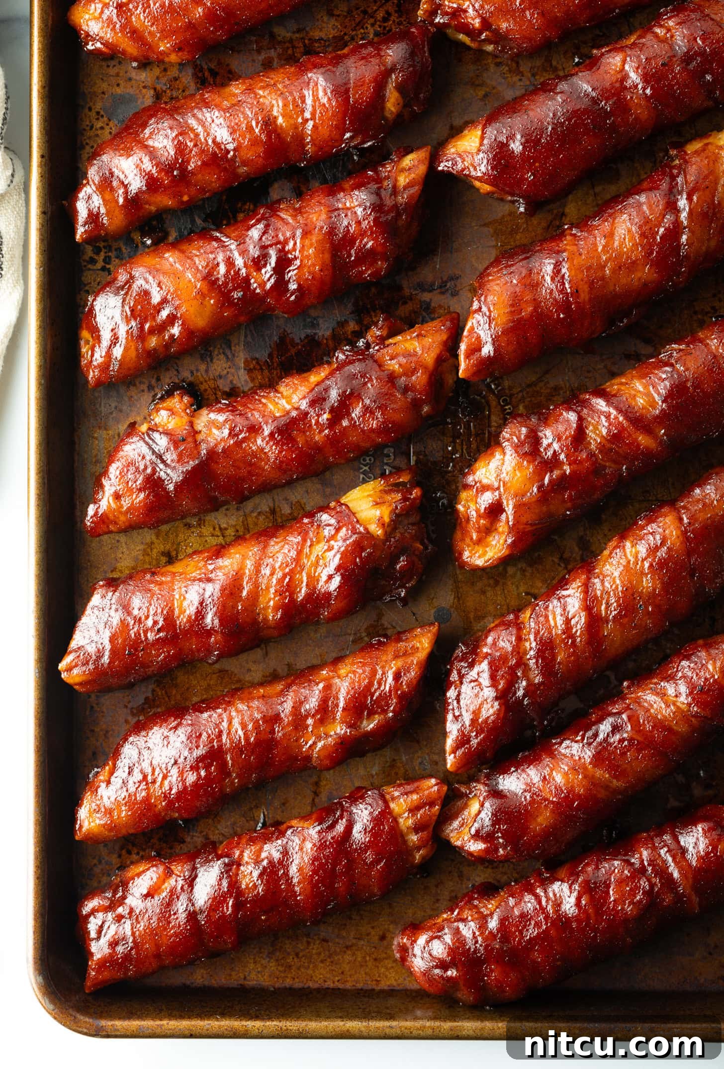 Top down view of 14 bacon wrapped smoked shells on a baking pan.