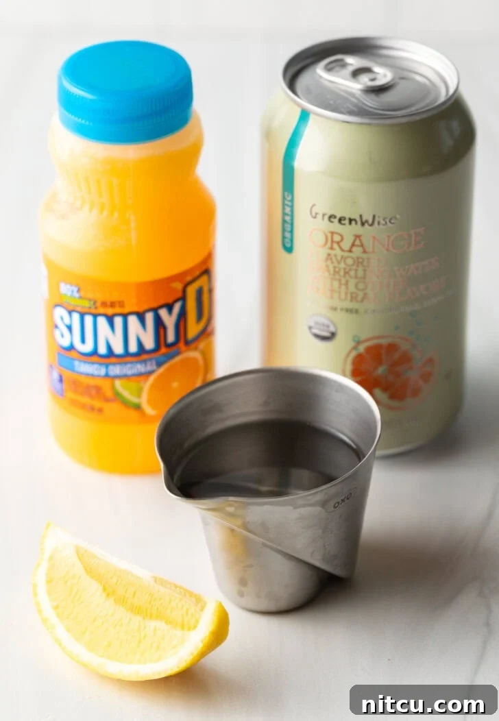 Recipe ingredients: Bottle of juice, metal cup with vodka, fresh orange wedge, and can of soda.