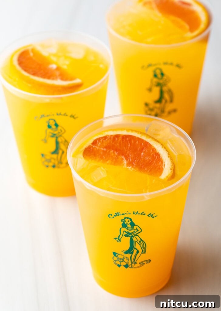 Three Sunny D Vodka Seltzer drinks, each in a glass cup with a slice of orange on top.