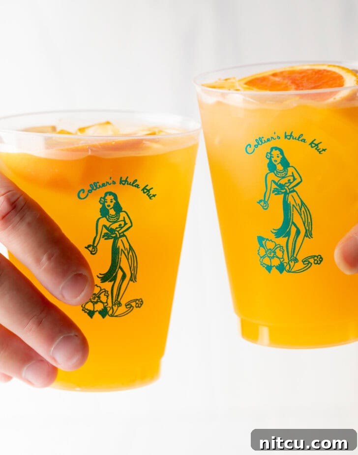 Two hands cheering with glasses of vodka, juice, and seltzer drinks.