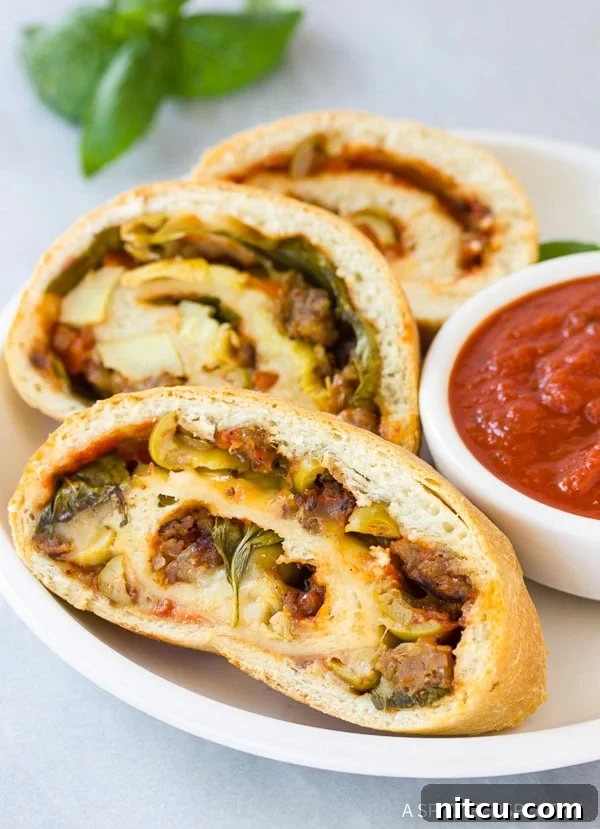 Homemade Stromboli with a golden crust, sliced to show cheesy filling. Perfect easy recipe for dinner or parties. Delicious classic Italian dish.