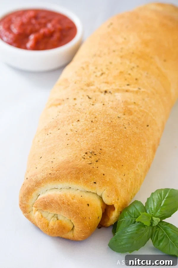 Close-up of a homemade Stromboli, golden brown and perfectly rolled, ready to be sliced and served.