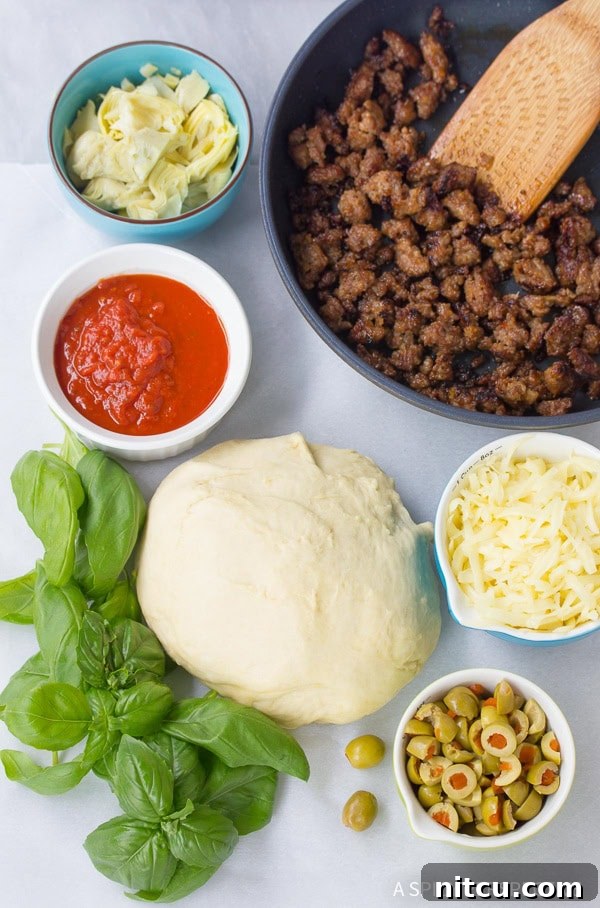 Fresh ingredients laid out for homemade Stromboli: pizza dough, Italian sausage, artichoke hearts, basil, olives, mozzarella, and marinara sauce.