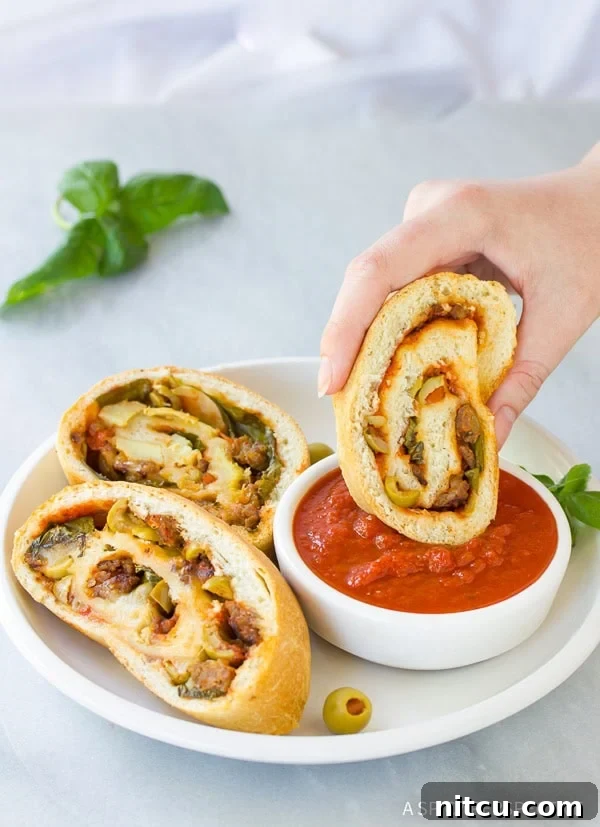 A freshly baked homemade Stromboli, golden and inviting, sliced and ready to serve with a side of marinara for dipping.