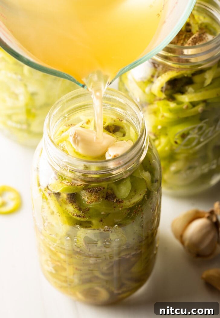 Pouring pickling brine into a jar of sliced peppers.