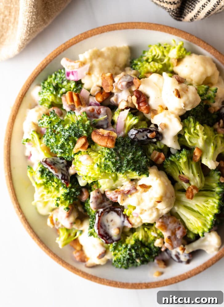 Top down view of a large bowl filled with appetizing broccoli cauliflower salad, showcasing its fresh ingredients and inviting texture.