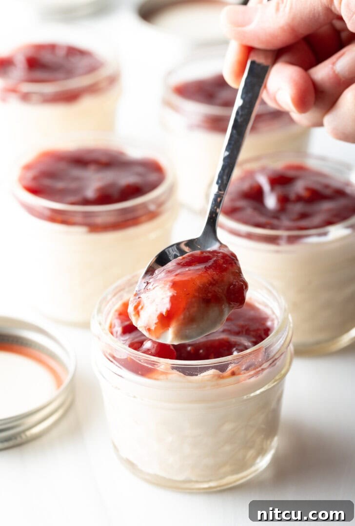 Metal spoonful of protein yogurt and raspberry jam to camera.