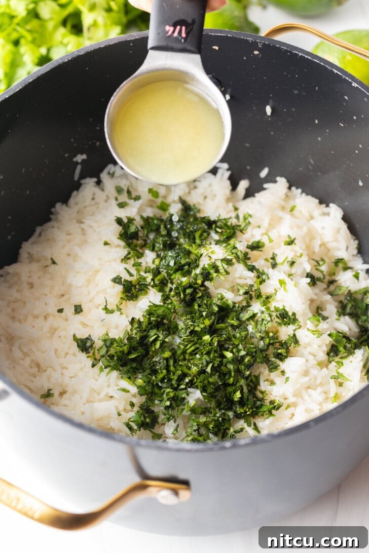 Adding lime juice from a measuring spoon over a pot with rice and chopped cilantro.
