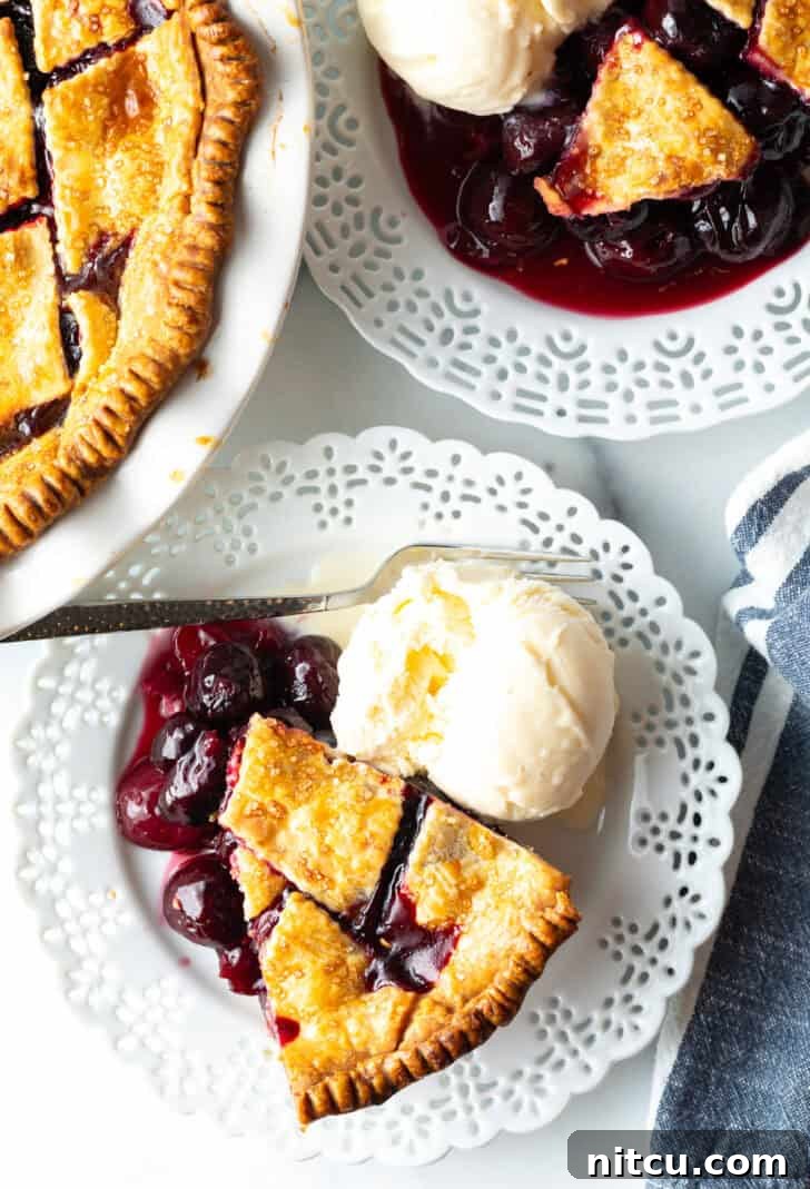 A top-down view of a perfect slice of homemade cherry pie with scratch-made filling, resting on a white plate, accompanied by a melting scoop of vanilla ice cream – an irresistible dessert.