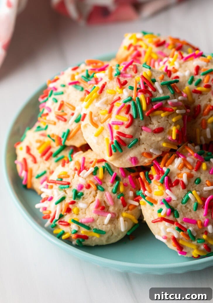 Blue plate piled with cookies covered in colorful sprinkles.