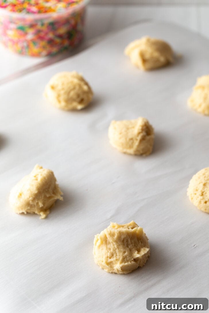 Several raw cookie dough balls on a baking sheet.